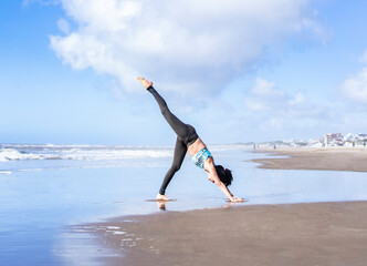 A woman practicing yoga on the water at the beach