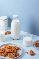 Milk in a glass and a bottle, cookies in a plate. Light blue bac