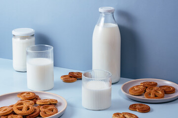 Milk in a glass and a bottle, cookies in a plate. Light blue bac