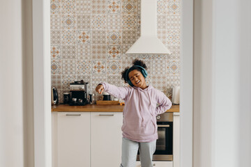 Cheerful black girl dancing in kitchen