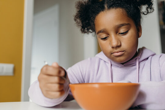 Indifferent black girl having breakfast