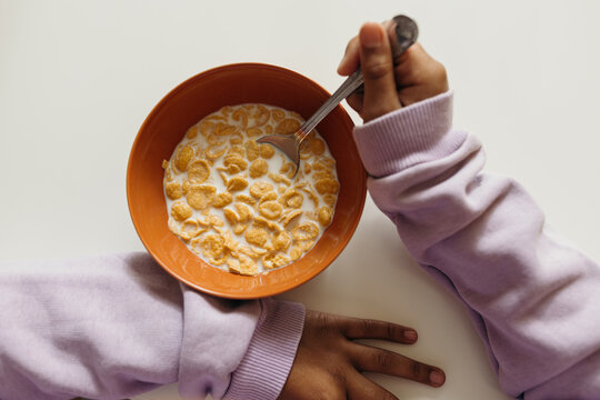 Crop girl eating cornflakes in morning