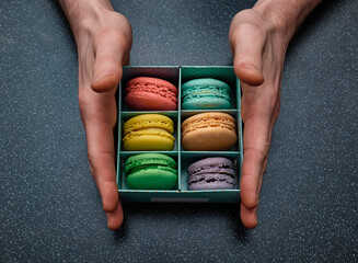 Anonymous hands holding box with macaroons