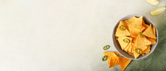 Bowl with tasty nachos on light background with space for text