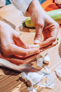 chef peeling garlic in kitchen.