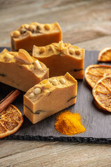Natural orange soap on the black and wooden background. Concept of making and using organic eco soap and cosmetics