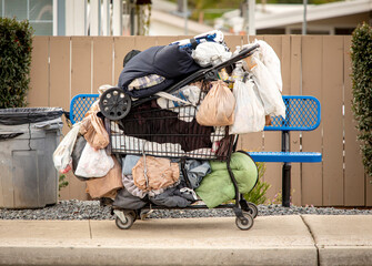 Homeless person’s belongingings in a shopping cart in a sidewalk