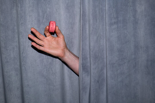 Anonymous hand holding pink macaroon 