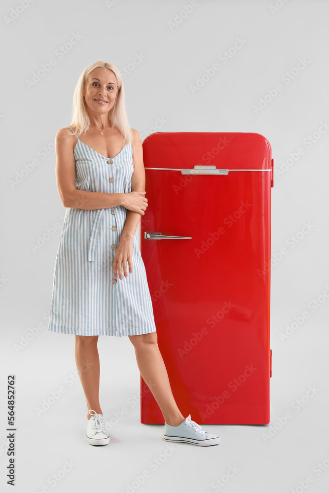 Sticker Mature blonde woman and retro fridge on light background