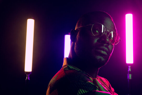 Stylish man in dark room with neon lights