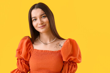 Young woman in stylish blouse on yellow background