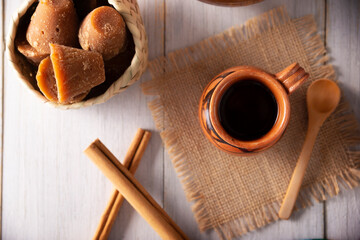 Fototapeta na wymiar Cafe de Olla. Traditional Mexican coffee and basic ingredients for its preparation, coffee, cinnamon and piloncillo, served in a clay cup called 