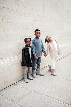 Siblings holding hands as and walking on the sidewalk