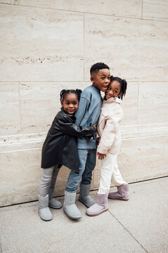 Sister hug brother as he hugs them back and smile