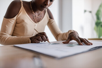 Black architect drawing line on draft