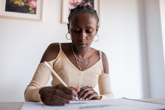 Focused black architect creating blueprint