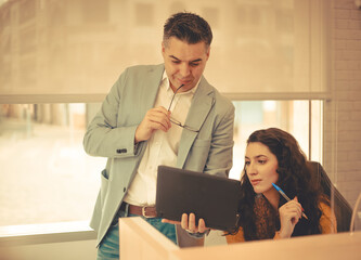 Image of a  woman and man checking data in a laptop at the office