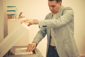 Young adult man using a photocopier at office