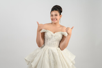 Fototapeta premium Young asian beautiful bride pose thumb up on white background