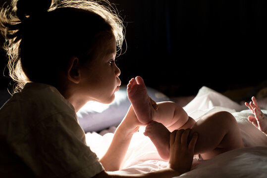 older child kisses the baby's feet. Family values