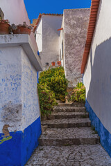 Ancient stone step between white mediterrean building in Obidos Portugal