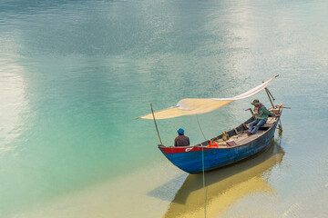 Obraz premium A singe blue fishing boat sitting on a large calm coastal lagoon at Lang Co in Vietnam