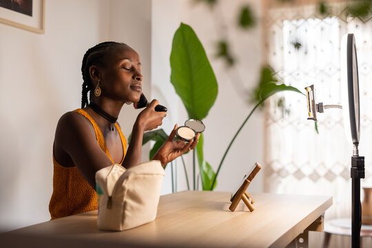 Black influencer applying makeup with closed eyes