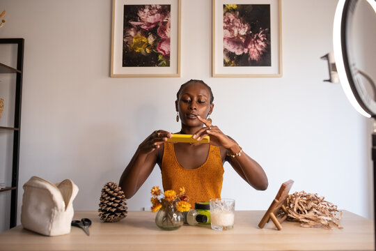 Black woman shooting cream near candle and flowers