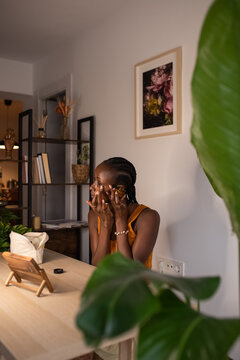 Black woman applying cream under eye