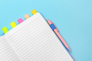 Notebook with sticky notes and pen on color background, closeup