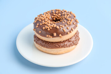 Plate with tasty chocolate donuts on color background