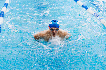 Fototapeta na wymiar hispanic young man swimmer athlete wearing cap and goggles in a swimming training at the Pool in Mexico Latin America 