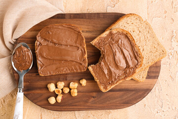 Wooden board of tasty toasts with hazelnut butter and nuts on color background