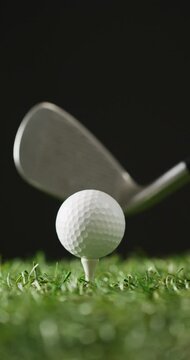 Vertical viedo of golf ball and club on grass and black background, copy space, slow motion