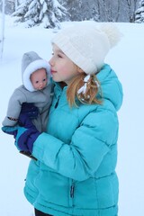 girl kissing her doll in snow