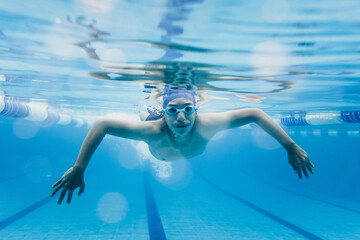 latin young teenager man swimmer athlete wearing cap and goggles in a swimming underwater training In the Pool in Mexico Latin America	
