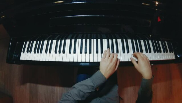 The student is learning to play the piano. A man with two hands plays a beautiful piano in the classroom close-up. Shot with a wide angle camera. Fish eye.