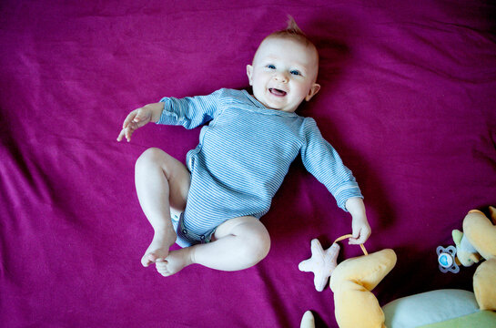 Happy baby having fun on bed, Kerroch, Brittany, France