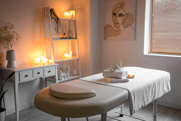 Interior of spa salon with couch, shelving unit and burning candles