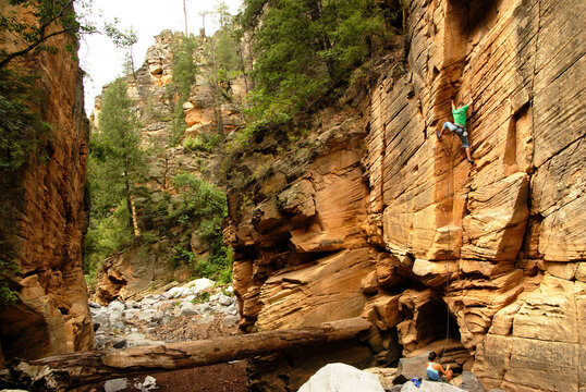 Patrick Brown climbs a bolted sandstone sport route in a slot canyon as Dana Ikeda belays in N. Arizona.