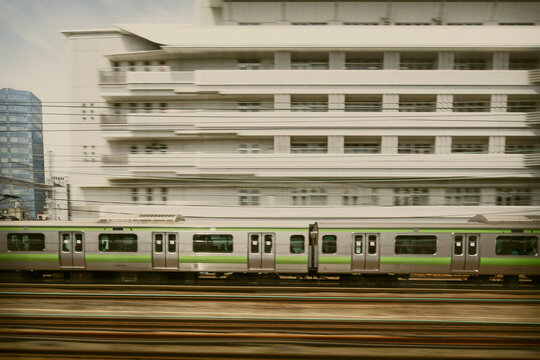 Japan bullet train runs over its track, blurry cityscape at the background gives the sense of speed.