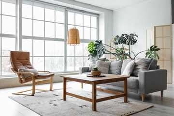 Interior of modern living room with grey sofa, armchair and palm tree
