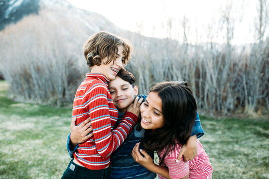 Little brother hugging two sisters one wants to get away