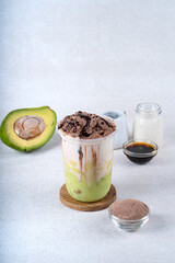 Iced chocolate milk smoothie cocktail with avocado juice on white rustic background
