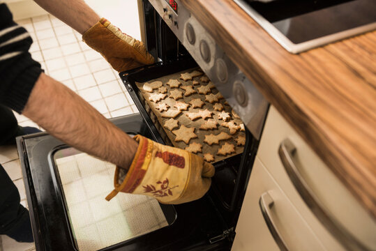 Close-up of a man taking out baked cookies from the oven, Munich, Bavaria, Germany