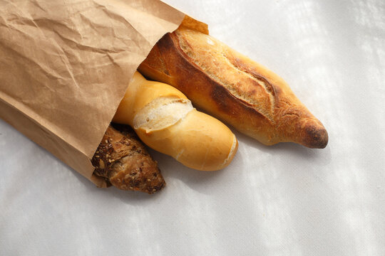rye, wheat, multigrain baguettes in  paper bag on white tablecloth