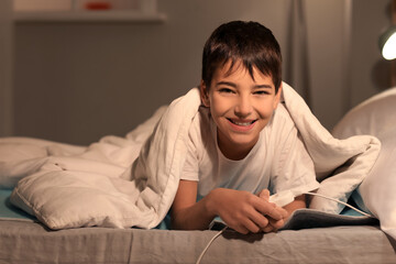 Fototapeta premium Little boy lying on electric heating pad in bedroom at night