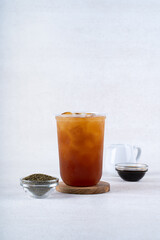 Iced black tea in plastic cup on white rustic background
