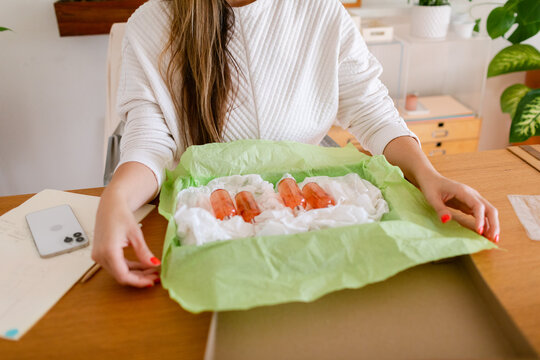 Female packing natural cosmetics at desk