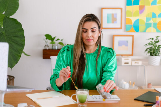 Woman adding lavender flowers to matcha latte at office